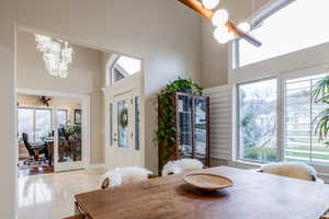 Dining area with hanging lights, a high ceiling, light tile patterned floors, and an office area