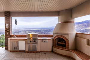 View of patio with an outdoor kitchen, a mountain view, and exterior fireplace