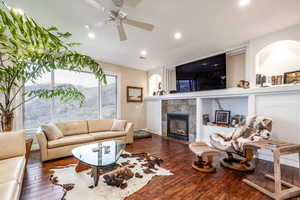 Living area with dark wood-style floors, ceiling fan, a fireplace, and recessed lighting