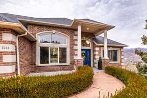 Entrance to property with brick siding and a shingled roof