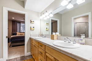 Ensuite bathroom with double vanity, a stall shower, and dark colored carpet