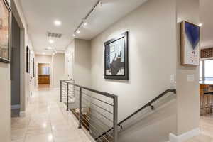 Hallway featuring an upstairs landing, light tile patterned flooring, and rail lighting