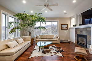 Living area with a ceiling fan, a tiled fireplace, hardwood / wood-style floors, and recessed lighting