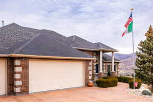 View of front of house with brick siding, roof with shingles, a garage, and concrete driveway