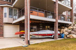 Back of property with a balcony, brick siding, an attached garage, and a yard