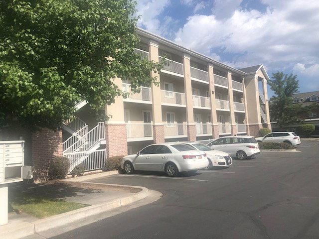 View of apartment building / complex with uncovered parking