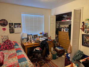 Bedroom with carpet, a textured ceiling, a desk, and a closet