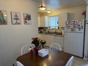 Dining space with a textured ceiling, ornamental molding, and light tile patterned floors