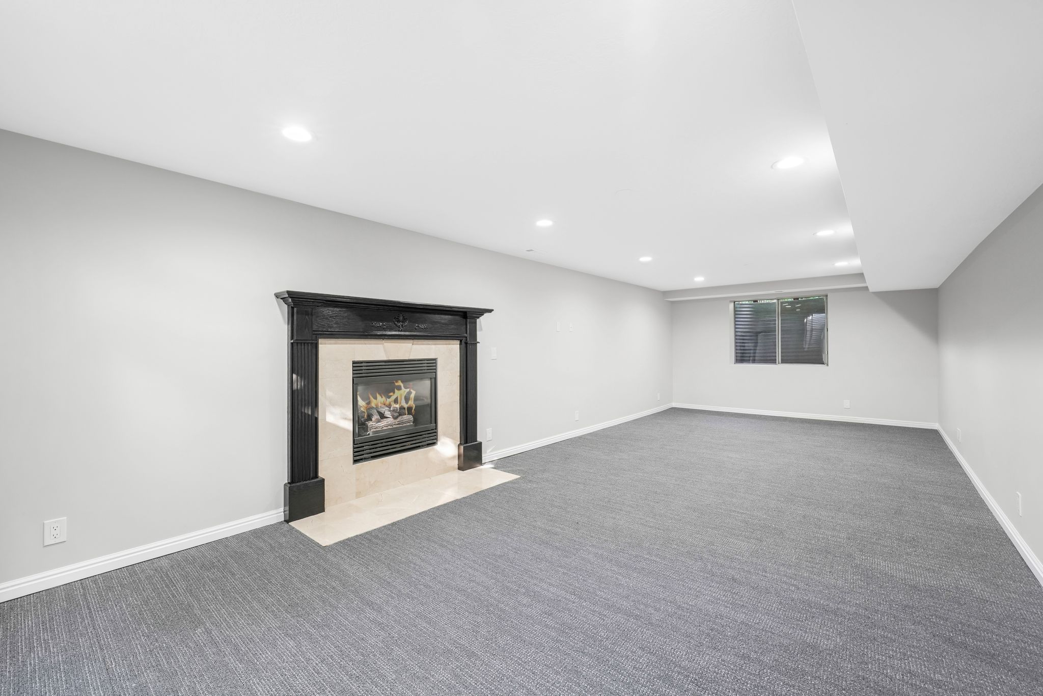 Finished basement with carpet, a tiled fireplace, and recessed lighting
