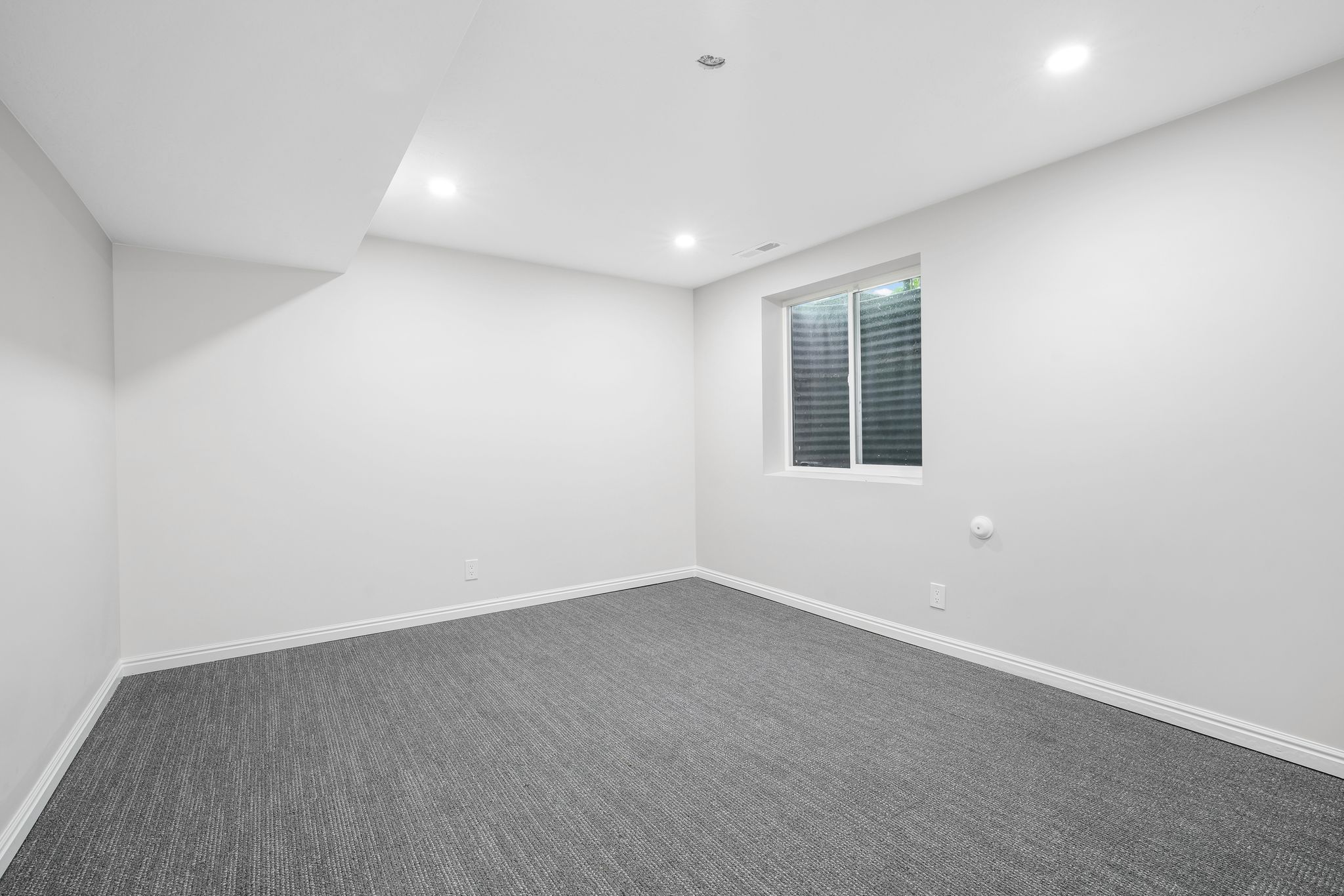 Empty room with dark carpet and recessed lighting