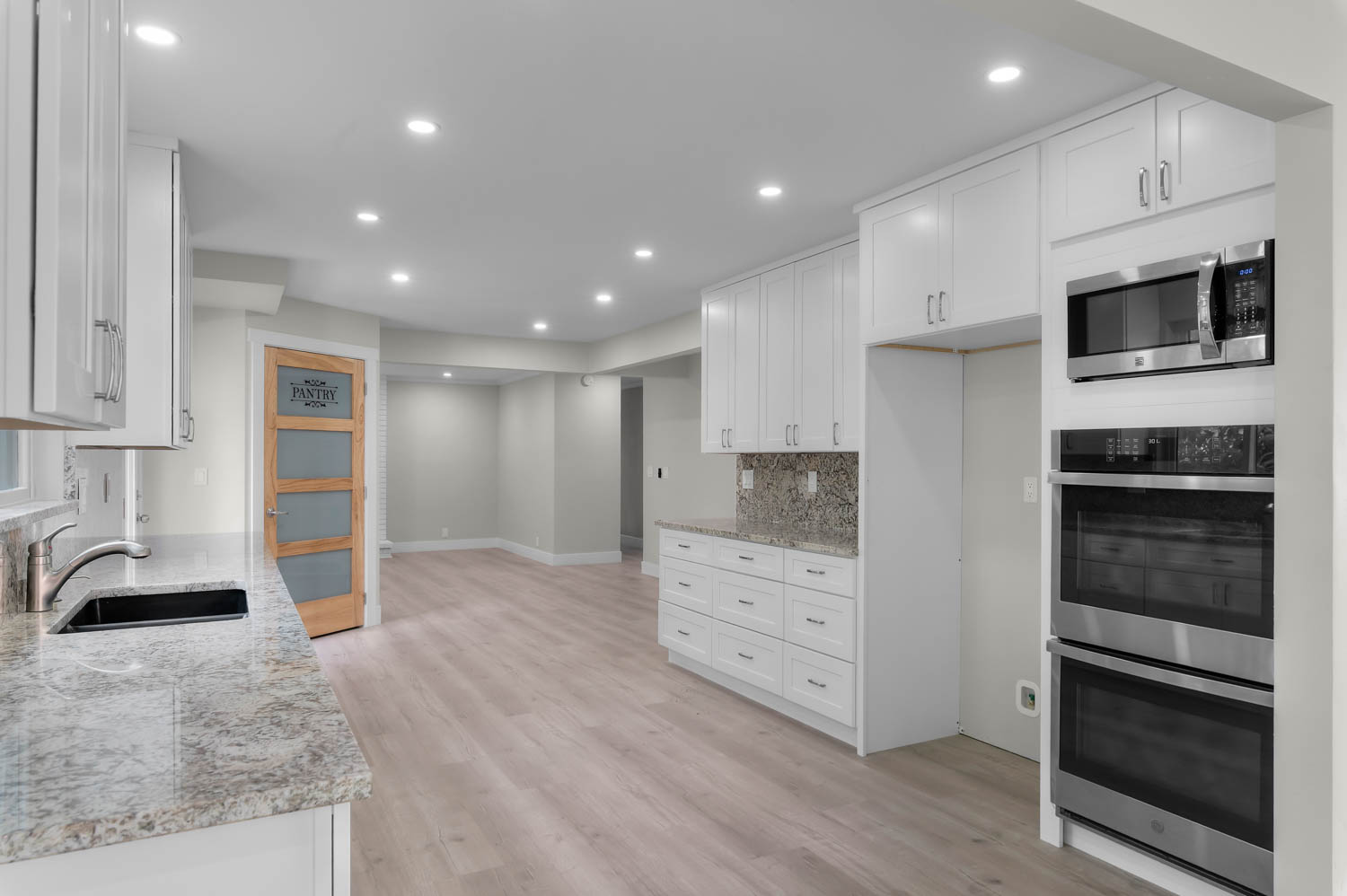 Kitchen featuring stainless steel appliances, white cabinetry, light stone counters, and recessed lighting