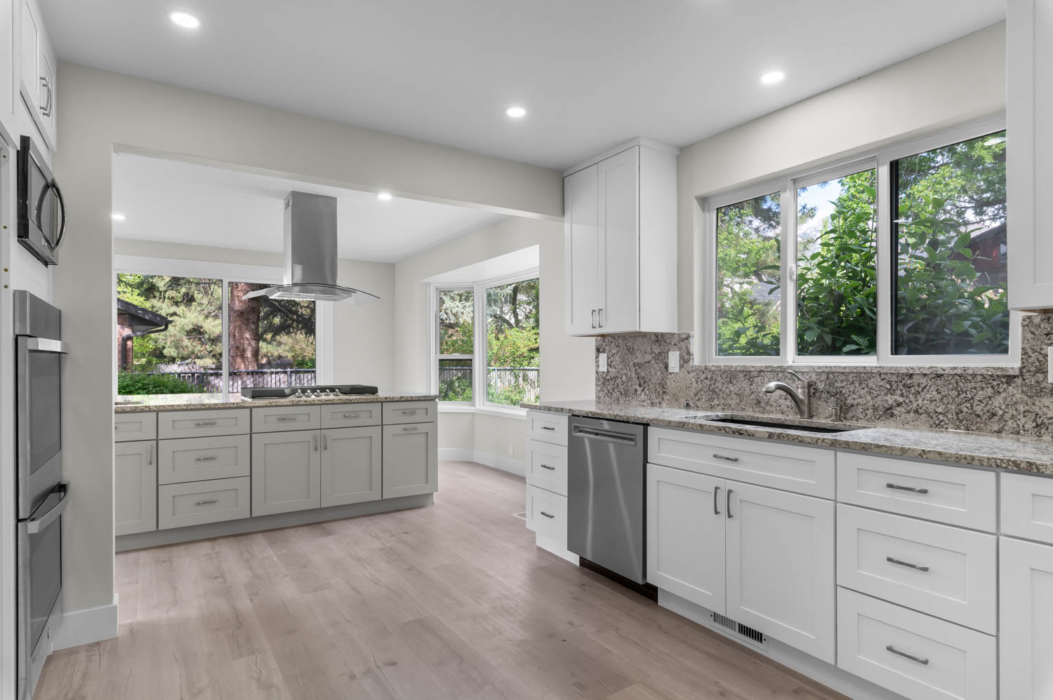 Kitchen with light stone countertops, white cabinets, island range hood, tasteful backsplash, and recessed lighting