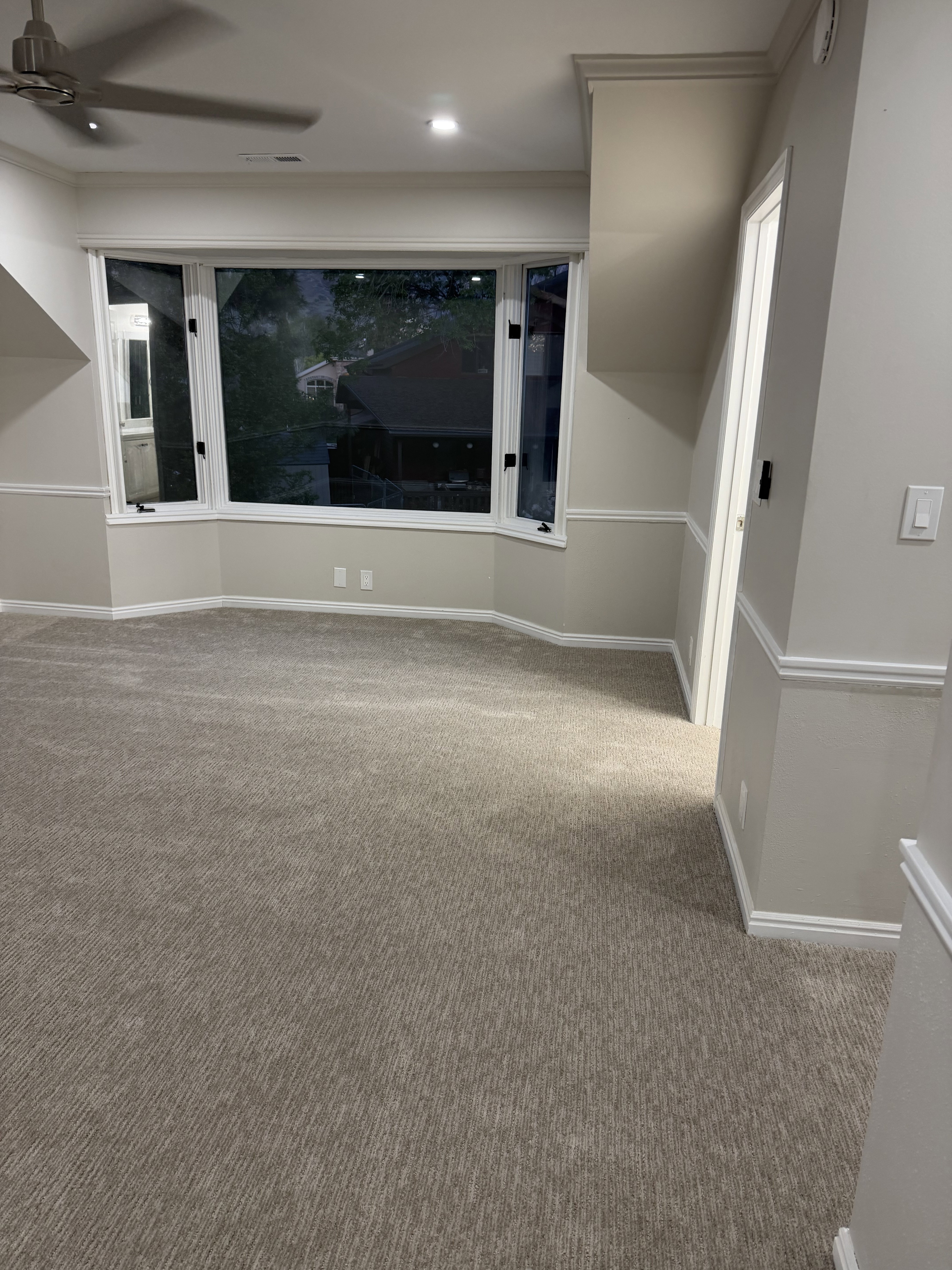 Empty room with carpet flooring and a ceiling fan