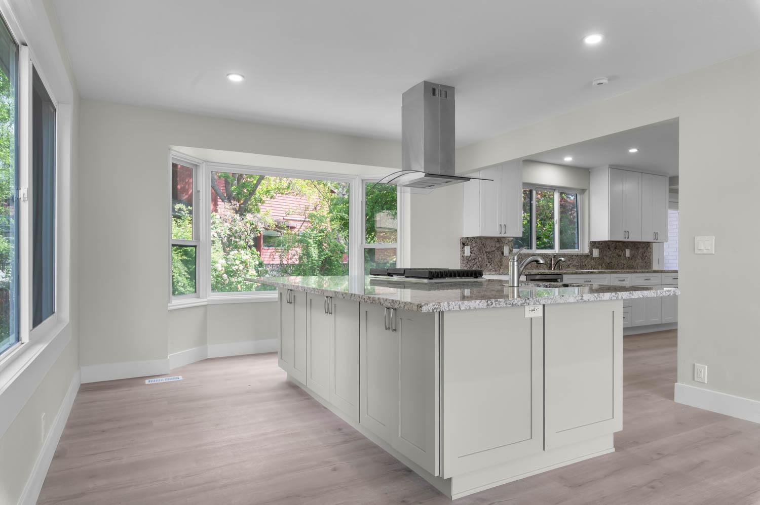 Kitchen featuring light stone counters, island exhaust hood, light wood-style floors, decorative backsplash, and recessed lighting