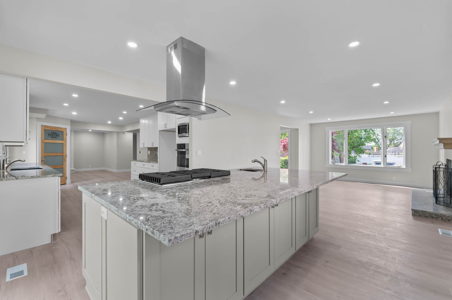 Kitchen with light stone counters, island exhaust hood, recessed lighting, open floor plan, and light wood finished floors
