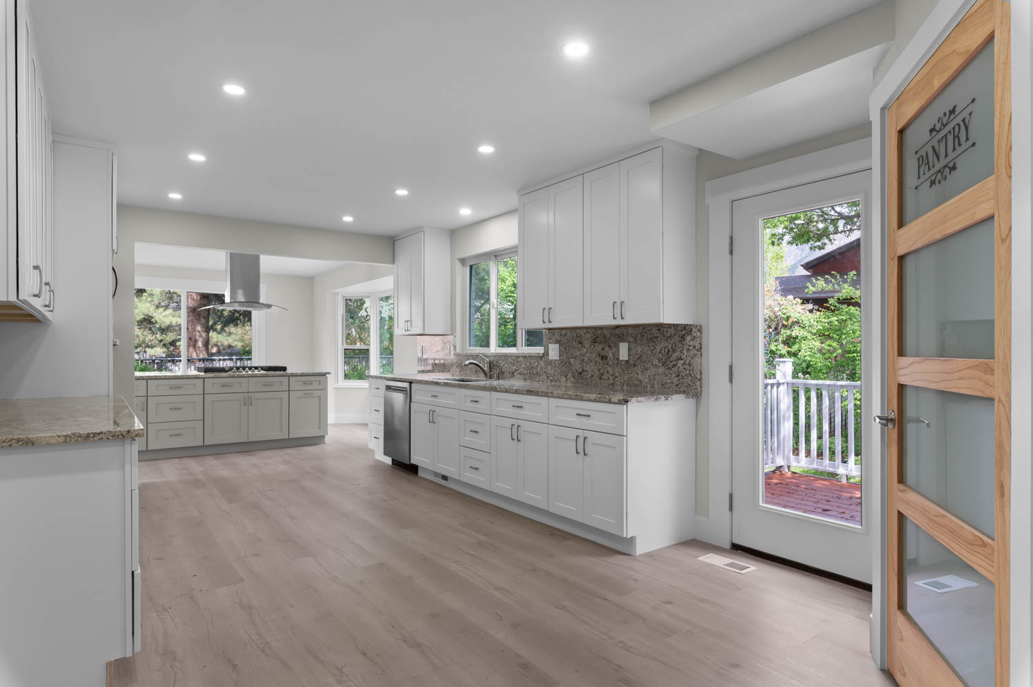 Kitchen featuring light stone counters, white cabinets, recessed lighting, and healthy amount of natural light