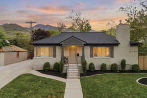 View of front of house featuring brick siding, a chimney, roof with shingles, and a mountain view