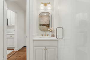 Full bath with vanity, dark wood-type flooring, and a shower stall