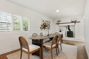 Dining area featuring wood-type flooring, a wood stove, and recessed lighting