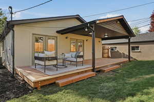 Back of property featuring a lawn, french doors, an outdoor living space, stucco siding, and a wooden deck