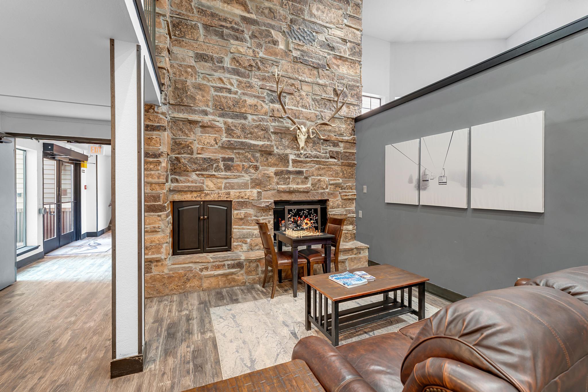 Living area with a stone fireplace, wood finished floors, and a high ceiling
