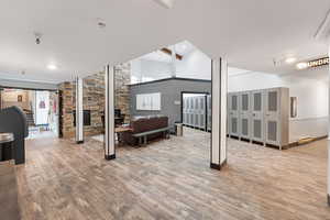 Living area with a high ceiling, light wood-style floors, a baseboard heating unit, and a stone fireplace