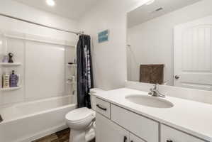 Bathroom with vanity, shower / bath combination with curtain, and dark wood-style flooring