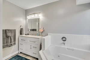 Full bathroom with vanity, a tub with jets, and light wood-type flooring