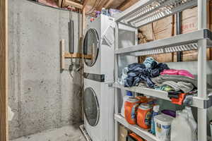 Laundry area featuring concrete floors and stacked washing machine and dryer
