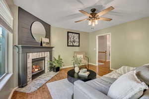 Living room featuring light wood-type flooring, a brick fireplace, and a ceiling fan
