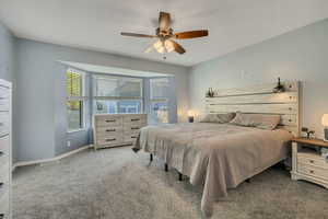 Carpeted bedroom with ceiling fan and baseboards