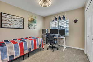 Bedroom featuring an office area, light colored carpet, and a closet