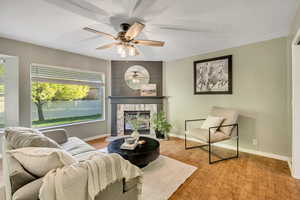 Sitting room with light wood-type flooring, a stone fireplace, a textured ceiling, and a ceiling fan