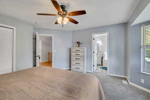 Bedroom with light carpet, ceiling fan, and ensuite bathroom