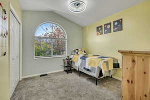 Bedroom featuring lofted ceiling, light colored carpet, and a closet