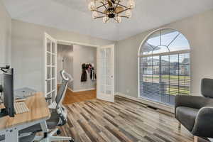 Home office with french doors, light wood-style flooring, and hanging lights