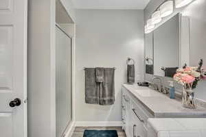 Full bath with vanity, a shower stall, and light wood-type flooring