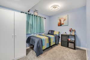 Carpeted bedroom with a closet and baseboards