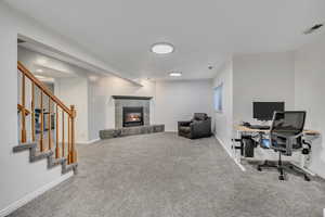 Home office featuring light colored carpet and a tiled fireplace