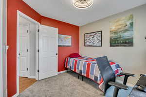 Bedroom with light colored carpet and a textured ceiling