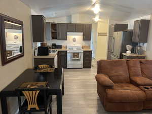 Kitchen featuring white gas stove, light countertops, freestanding refrigerator, and light LVT flooring