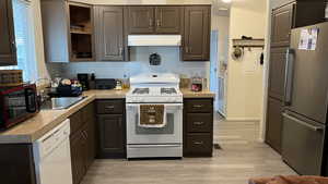 Kitchen with white appliances, light LVT flooring, and light countertops