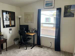 Office space with light carpet and vaulted ceiling