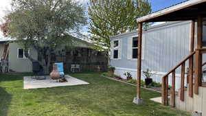 View of green lawn with a patio and a wooden deck