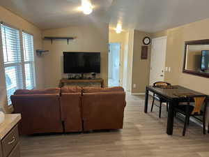 Living area with vaulted ceiling and light LVT floors