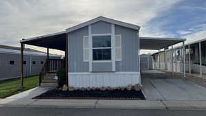 View of front of house featuring a carport, driveway, a storage shed, and a porch