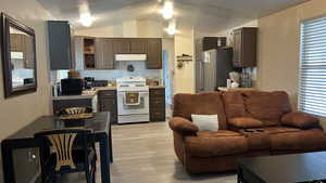 Kitchen featuring gas range gas stove, light countertops, light LVT flooring, black microwave, and freestanding refrigerator