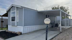 View of side of property featuring a storage unit, an attached carport, and concrete driveway