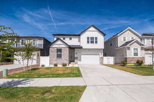 View of front facade with a gate, stone siding, a garage, and concrete driveway