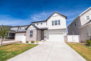 View of front of property with a gate, stone siding, an attached garage, and driveway